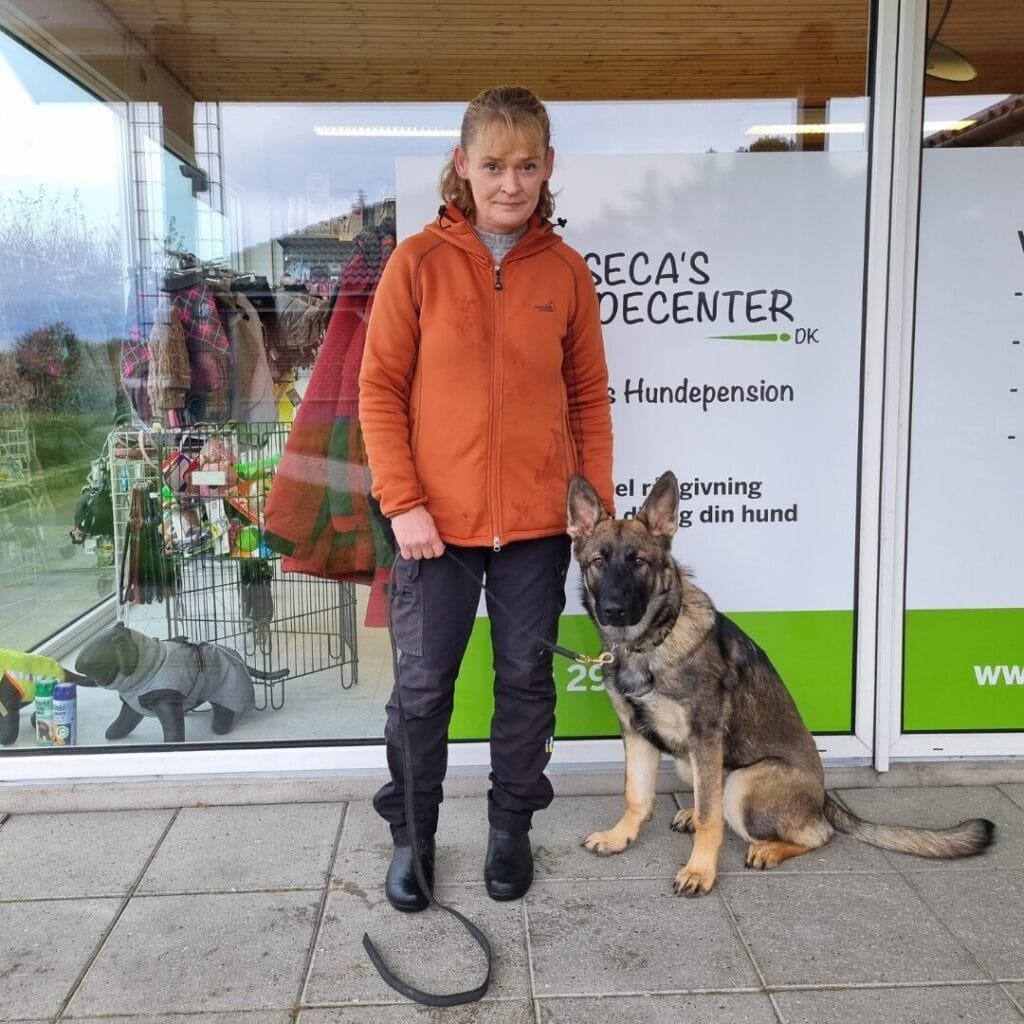 Kvinde med schæferhund foran dyrebutik